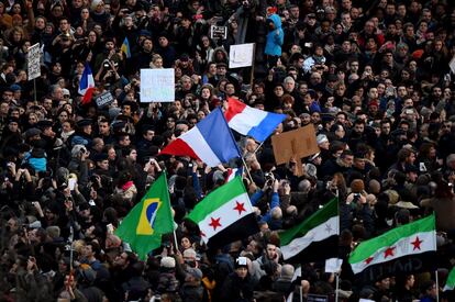 Bandeiras da França, do Brasil e do movimento autônomo da Síria durante o protesto em Paris.