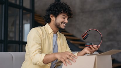 Un hombre sacando unos auriculares de una caja.