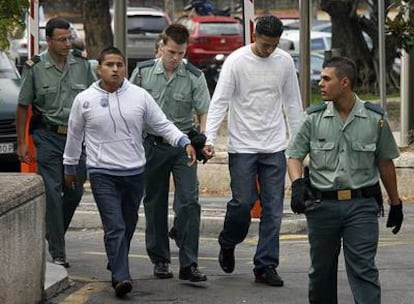 Agentes de la Guardia Civil llevan esposados a dos presuntos latin king acusados de asesinar a un joven de una banda rival.