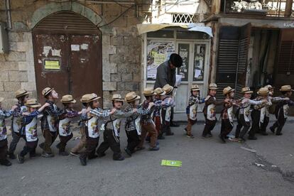 Un grupo de niños judíos ultraortodoxos disfrazados marchan en fila en la calle durante su celebración escolar de Purim, en Jerusalén, Israel.