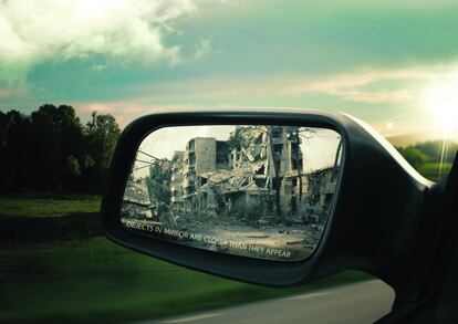 Por el retrovisor de un coche se pueden ver las ciudades en ruinas que dejan tras de sí los ataque sobre la población civil en Siria, mientras que en la dirección de la marcha el paisaje es más apacible.