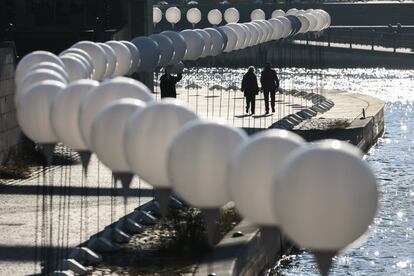 Dos personas caminan junto a una interminable fila de globos blancos, parte del proyecto “Frontera de Luz”. Esta instalación señala el trazado por donde transcurría el muro que durante 28 años dividió la ciudad de Berlín. Esta construcción, símbolo de la guerra fría, que marco la ciudad y condicionó su urbanismo va a ser recordada ésta noche con más de 8.000 globos blancos que recorrerán su antiguo trazado.