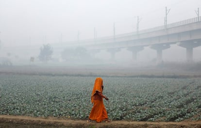 Una mujer camina a través de un campo con una densa niebla de contaminación en Nueva Delhi (India).