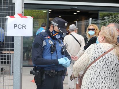 Un policía municipal pide este martes la documentación a una mujer antes de entrar al Centro Cultural Lope de Vega, en Puente de Vallecas, uno de los barrios confinados en Madrid.