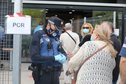 Un policía municipal pide este martes la documentación a una mujer antes de entrar al Centro Cultural Lope de Vega, en Puente de Vallecas, uno de los barrios confinados en Madrid.