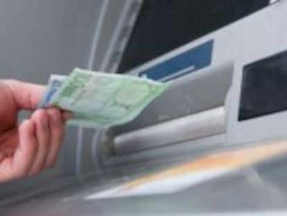 Un hombre saca dinero de un cajero automático.