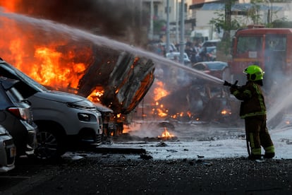 A firefighter extinguishes burning vehicles following a Palestinian attack on Ashkelon.