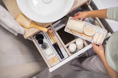 Una mujer organizando el interior de su armario del cuarto de baño. Las nuevas filosofías de organización de aires minimalistas han ganado adeptos y se han extendido del interior de los hogares a cualquier faceta de nuestras vidas.