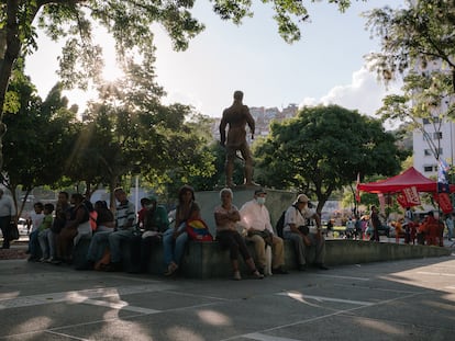 Vecinos descansan cerca de una estatua de Simón Bolívar mientras voluntarios instruyen sobre cómo votar el 21 de noviembre, en Caracas.