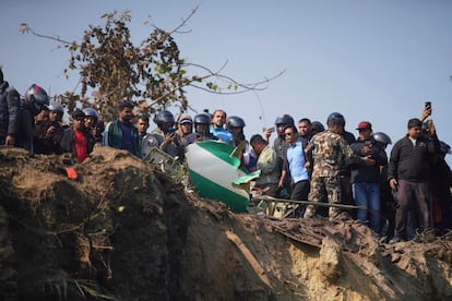 Residentes locales junto a los restos del avión accidentado en Pokhara, este domingo. 