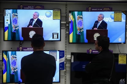 Dois homens assistem ao discurso de Temer, nesta quinta.