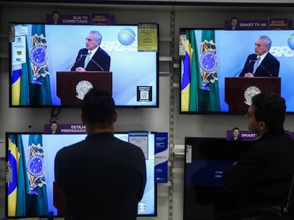 Dois homens assistem ao discurso de Temer, nesta quinta.