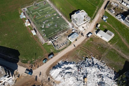 Vista aérea de un edificio destruido y de un campo de fútbol donde se refugian los residentes afectados por los terremotos en Azmarin (Siria), este miércoles.