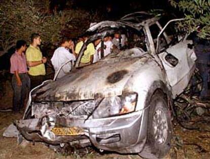 Un grupo de palestinos observa el estado en que quedó un coche tras la explosión que mató a tres miembros de Al Fatah.