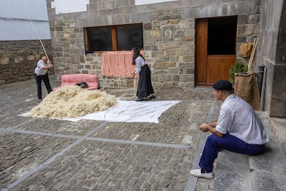 Vecinos de Ochagavía golpean con varas de madera la lana recién esquilada.