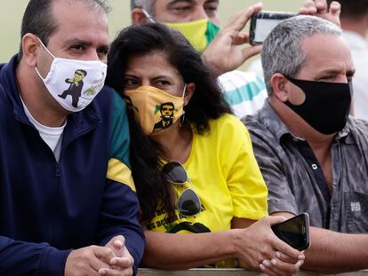 Seguidores de Bolsonaro con mascarillas de Bolsonaro esperan este lunes al presidente ante su residencia, en Brasilia.