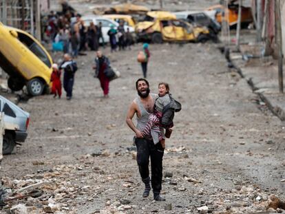 Un hombre huye con su hija de un lugar controlado por el Estado Islámico en Mosul, el sábado