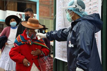 Un funcionario electoral mide hoy la temperatura a una mujer antes de ingresar a su local de votación, en Cusco.