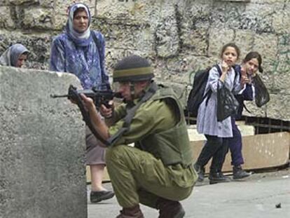 Unas niñas se tapan los oídos mientras un soldado israelí dispara contra los palestinos en Hebron.