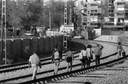 Vecinos de San Nicasio caminan por las vías del tren para ir a la estación de cercanías en 1995.