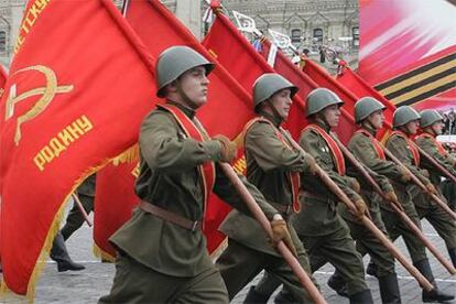 Soldados rusos con uniformes de la II Guerra Mundial marchan con banderas comunistas por la plaza Roja de Moscú.