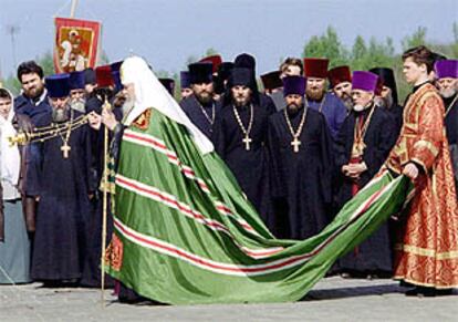 Un ayudante lleva la capa del patriarca de la Iglesia ortodoxa rusa, Alejo II, durante la bendición de un templo.