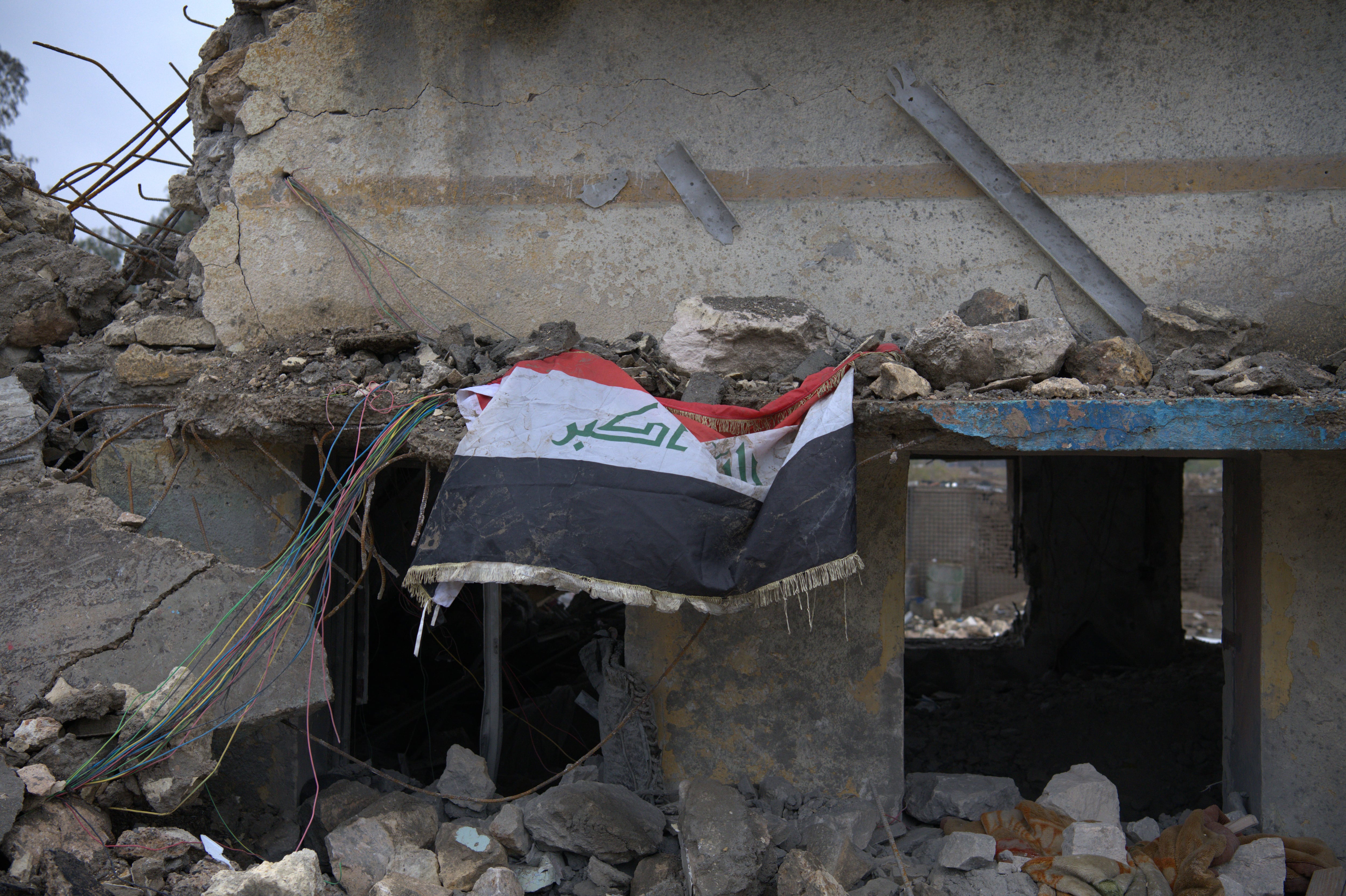 La bandera de Irak sobre los escombros de la clínica de la base Habbaniya del ejército iraquí, tras ser bombardeada por un avión estadounidense el pasado 26 de marzo.