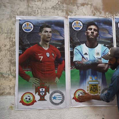 A football fan pastes posters of football players (L-R) Portugal's Cristiano Ronaldo, Argentina's Leo Messi and Brazil's Neymar Jr. on a wall ahead of the Qatar 2022 FIFA World Cup football tournament, in Karachi on November 12, 2022. (Photo by Rizwan TABASSUM / AFP)