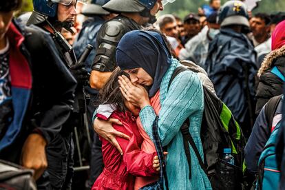 Una mujer consuela a su hija que llora entre la multitud.