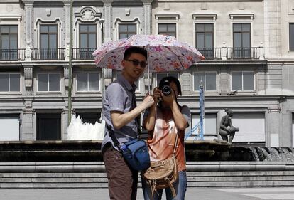 Una pareja de turistas se protege del sol bajo un paraguas muy colorido. El Centro de Emergencias de la Comunidad de Madrid 112 ha avisado a los municipios y organismos de la región de la ampliación de la alerta, que pasa al nivel naranja, para que informen a los ciudadanos y tomen las medidas oportunas para prevenir los riegos existentes.