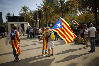 Una mujer sostiene una estelada mientras abraza a un hombre durante la concentración.