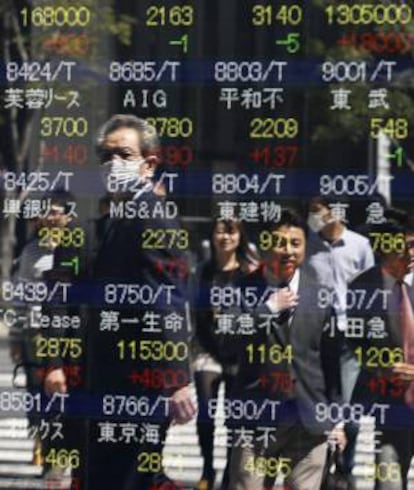 Peatones reflejados en una pantalla con los resultados de la Bolsa de Tokio, en Japón. EFE/Archivo