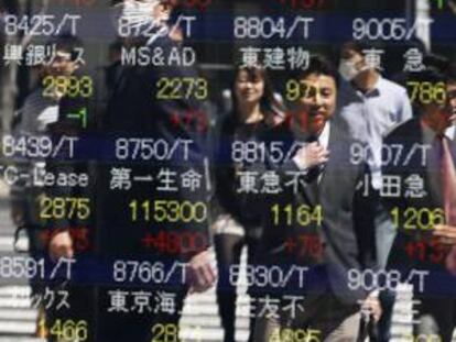 Peatones reflejados en una pantalla con los resultados de la Bolsa de Tokio, en Japón. EFE/Archivo