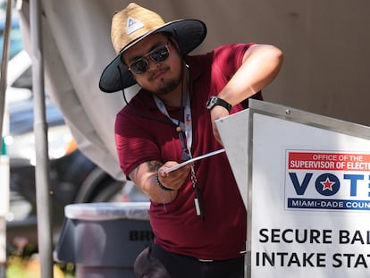 An election worker drops a ballot in Doral, Florida