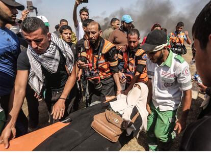 Manifestantes palestinos y paramédicos llevan en camilla a una mujer herida por las tropas israelíes.