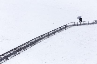 Un hombre sube unas escaleras bajo una intensa nevada caída hoy en Ávila, España.