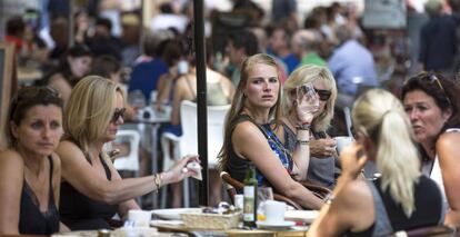 Varios turistas se refrescan en una terraza junto a La Lonja de Valencia. 