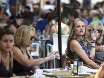 Varios turistas se refrescan en una terraza junto a La Lonja de Valencia. 