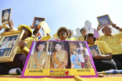Varios ciudadanos posan con retratos del rey Rama X y la reina Suthida de Tailandia en la ceremonia de coronación.