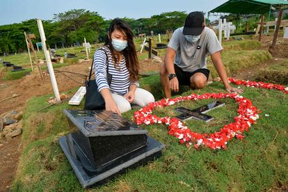 Tirsa Manitik (izquierda) y Erik Alexander (derecha) visitan la tumba de su bebé que dio positivo por covid-19 antes de morir, en el cementerio de Tegal Alur en Yakarta.