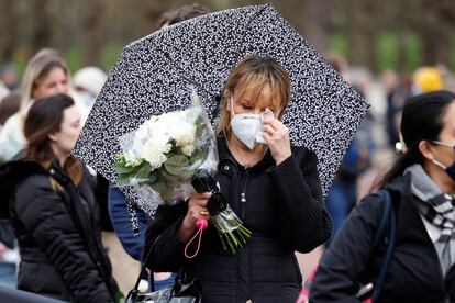 Una mujer espera en fila para rendir un tributo con un ramo de flores en el exterior del palacio de Buckingham, este sábado.