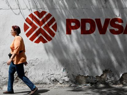 Uma mulher caminha em frente ao logotipo da petroleira venezuelana PDVSA em Caracas.