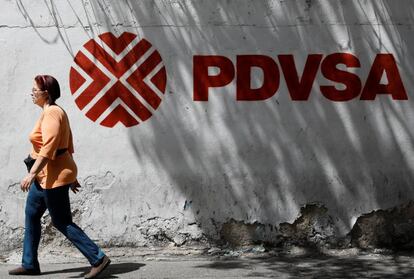 Uma mulher caminha em frente ao logotipo da petroleira venezuelana PDVSA em Caracas.
