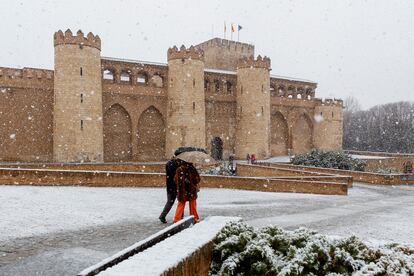 Una pareja camina bajo la nieve que ha empezado a caer a media mañana de este viernes en Zaragoza.