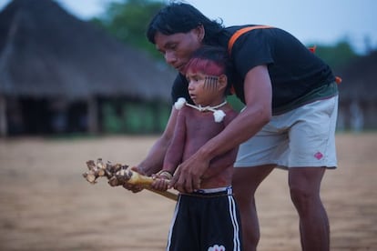 O pai ensina o garoto a lutar e o incentiva a não fugir da batalha. Nas mãos deles, a raiz usada para a luta.