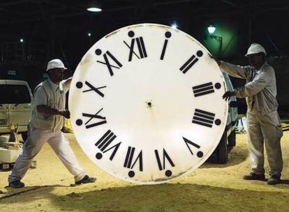 Dos operarios trasladan la restaurada esfera del reloj de la Catedral de Santa María.