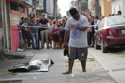 A man cries near a body covered on the ground, in Durán, Ecuador, on July 20, 2023.