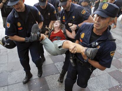 Cuatro agentes trasladan a una chica durante el desalojo de la Puerta del Sol.