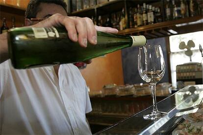 Un camarero sirve un vaso de <i>txakoli</i> en un bar de Vitoria.