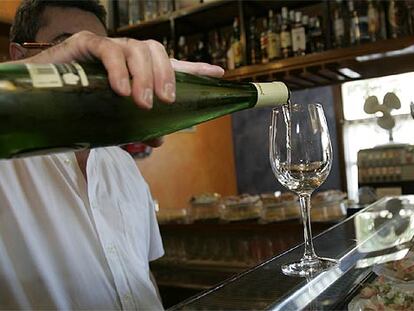 Un camarero sirve un vaso de <i>txakoli</i> en un bar de Vitoria.